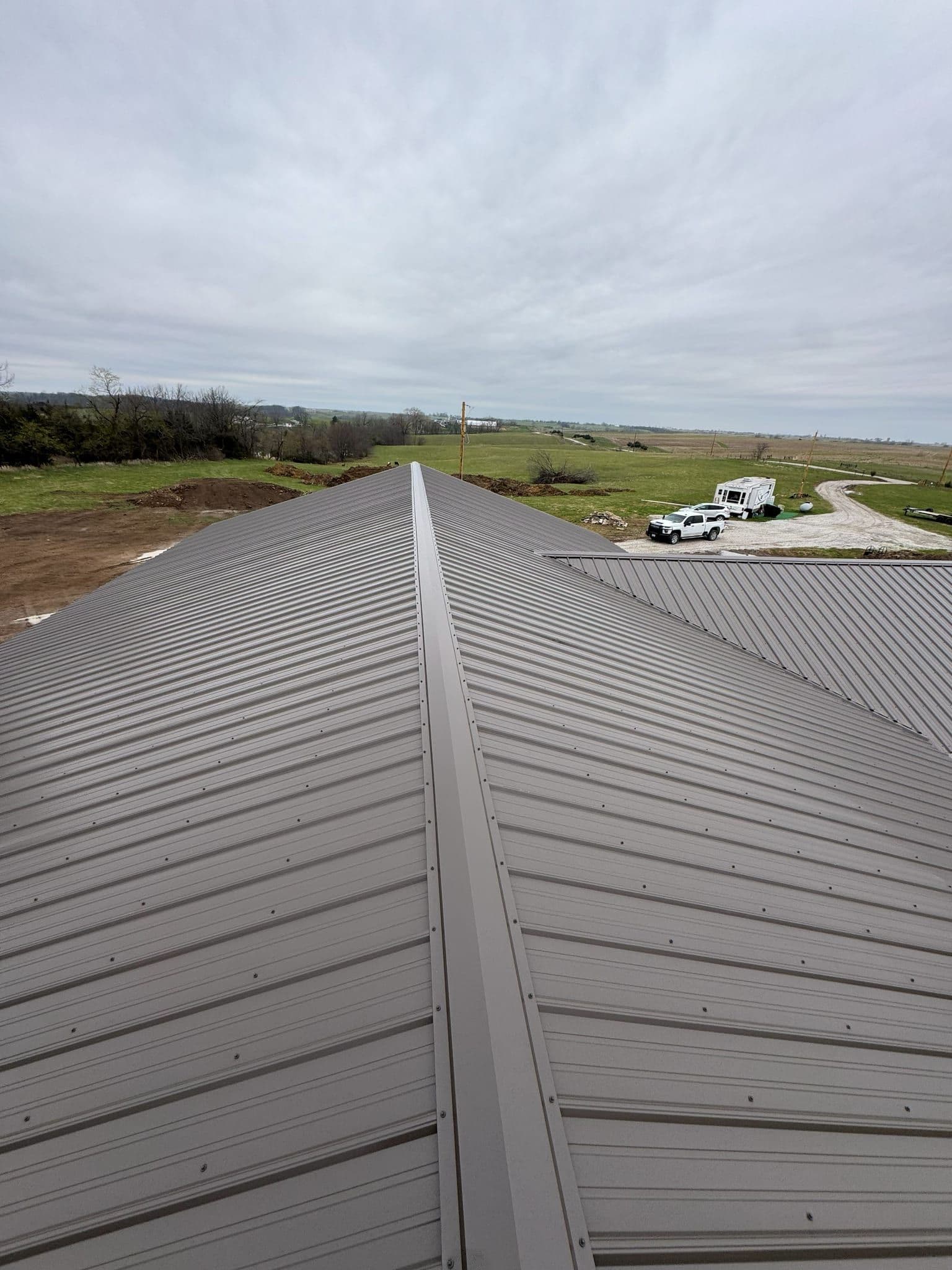 Standing-seam metal roof photographed along the ridge, panel lines running straight to the eave